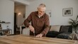 © LimeSky - Tall photo of a pleasant older man repairing a table with a screwdriver, wearing brown clothing, enjoying leisure time in a large indoor space.