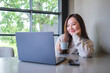 © Farknot Architect - Portrait image of a woman drinking coffee while working on laptop computer