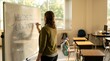 © Deki - Female teacher writing welcome message on whiteboard in classroom