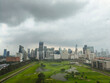 © jeera - Aerial view of cityscape featuring a golf course with lush green grass at its center, set against a backdrop of dark grey rain clouds filling the sky.