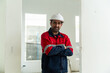 © Leny Studio - Asian construction worker wearing safety helmet and uniform stands confidently at construction site with arms crossed showing professionalism and safety awareness