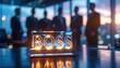 © Olga Gorkun - Illuminated boss sign on office table with blurred executives in background representing authority and corporate power