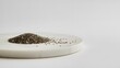 © GROW HIGH - Pile of raw organic black chia seeds resting on a smooth white marble round plate
