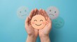 © Sukon - World mental health day concept featuring a happy smile face held in hands against blue background.