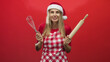 © Krakenimages.com - Woman holding whisk and rolling pin, smiling with mouth open, wearing santa hat and checked apron in studio; holiday baking joyful.