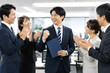 © michi_japan - 昇進や仕事の成功を同僚に祝福される日本人会社員