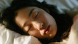 © Kowit - A close-up of a woman sleeping peacefully on a pillow with soft natural light highlighting her face and closed eyes.