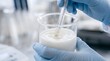 © Jo-El - Cosmetic Chemist Hands Testing Skincare Emulsion pH Level with Glass Electrode Probe in Laboratory Beaker, Macro Quality Control