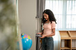 © Kawee - African American teenage girl stands by a bookshelf, carefully selecting a book.