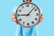 © Pixel-Shot - Healthcare professional holding a large wall clock, time management and scheduling in medical services