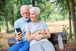 © Lumos sp - Happy active senior couple having fun using smartphone and wearing sportswear, after having an exercise sport activity outdoors