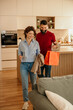 © La Famiglia - Couple arriving home from shopping, smiling and happy