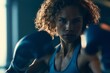 © Lightning - Powerful female boxer with intense gaze wearing blue gloves in a dark gym, embodying strength and determination.