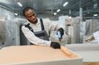 © Serhii - African american Furniture maker upholstering sofa in factory warehouse