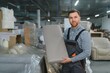 © Serhii - Furniture maker holding sofa cushion in factory warehouse