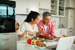 © Marko Geber - Couple cooking together and following online recipe in home kitchen