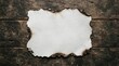 © AmenaStock - Rectangular piece of old paper with burnt edges and charred borders placed centered on a dark weathered wooden plank background, surface view
