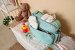 © Pixel-Shot - Baby bag with accessories on chest of drawers near beige wall in room