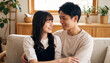 © Jesse_4160 - Young Japanese couple in love smiling and looking at each other while relaxing together on a cozy couch in a bright living room