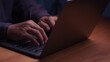 © ParinPIX - Close up of male hands typing on a laptop computer keyboard at night. Working late on modern business technology, internet connection, remote work, and online digital network communication.