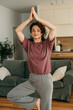 © La Famiglia - Woman practicing yoga tree pose meditation at home