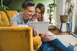 © Westend61 - Smiling couple using tablet PC at home