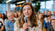© Maksym - Female founder fielding a condescending question from an audience member at a startup panel event, standing composed and sharp at a microphone, the room watching as she dismantles the bias embedded