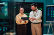 © Zamrznuti tonovi - Two it professionals collaborating, analyzing data on a tablet in a modern data center server room with glowing server racks