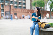 © Tj - Young Asian woman student traveler sitting and reading book, pointing and exploring historical Tha Phae Gate and old town city, enjoying tourism and education abroad