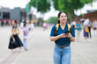 © Tj - Asian woman tourist walking on a city street, exploring and discovering new places while looking for directions or information using her smartphone, traveling alone