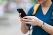 © Tj - Young woman holding smartphone outdoors, messaging, browsing and connecting; digital communication, mobile technology, and online interaction concept for modern lifestyle