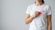 © Alya - Young woman wearing a white t shirt holds a pink ribbon on her chest to support breast cancer awareness month campaigns for health education and medical solidarity against cancer disease globally now.