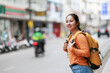 © Tj - Young Asian woman backpacker exploring city street, smiling, looking away, enjoying urban travel adventure, experiencing new cultures, walking outdoors