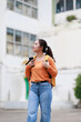 © Tj - Young asian woman exploring a city street. Carrying a backpack and smartphone. Looking up at surrounding architecture while enjoying an urban journey