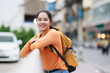 © Tj - Young Asian woman backpacker traveler exploring city street, smiling, enjoying her leisure journey, representing tourism, vacation, and urban lifestyle discovery