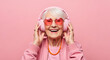 © MdAfzal - Happy senior woman wearing headphones. Elderly lady listening to music with pink glasses.