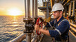 © Taras Roshchuk - A man wearing a hard hat and goggles is turning a valve on an oil platform. The sun sets in the background, casting light on the ocean waves. He focuses on his task