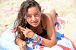 © Westend61 - Portrait of teenage girl with wet hair lying on towel on the beach