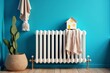 © Сергей Белый - Cozy Room Decor: Heating Radiator with Model House and Knitted Scarf Against Vibrant Blue Wall
