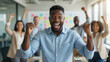 © Iryna - Businessman celebrating success with raised fists in modern office, teamwork achievement and corporate victory