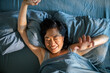 © Davor - Smiling woman stretching in bed at home