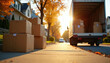 © Maryna - Cardboard boxes stacked on sidewalk next to moving truck parked on sunny suburban street. Brown parcel containers wait for loading during house relocation process. Residential neighborhood road