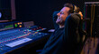 © Bluum - Man music producer sitting in recording studio with headphones. Sound engineer listening to track on console mixing board. Professional music production and media industry creative work