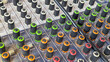 © Maule - Close up view of colorful control knobs on an analog sound audio mixer console board in a music recording studio or live event setting.