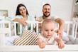 © Pixel-Shot - Happy young family and cute little baby sitting in crib at home