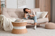 © Pixel-Shot - Young pretty woman reading magazine and resting on sofa in living room