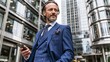 © wilson - Middle aged handsome businessman in blue checkered three piece suit holding smartphone standing outside modern city office building looking confidently into distance