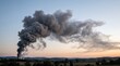 © ASEP - Large column of black smoke billows into the evening sky from a distant industrial fire, creating an ominous scene at dusk