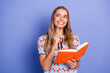 © deagreez - Young woman student smiling while holding orange notebook and pen against blue background expressing creativity and learning vibe
