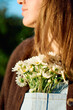 © Edson family/Stocksy - Detail of a girl holding white daisy blossoms in her clothes